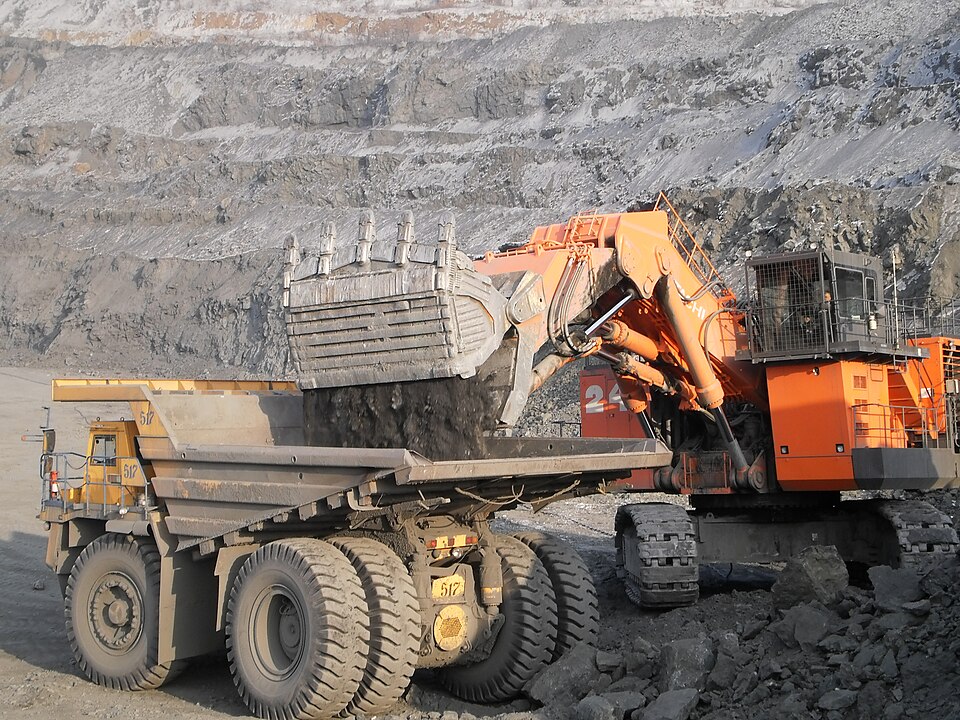 Ekskavator tambang memuat material ke truk angkut